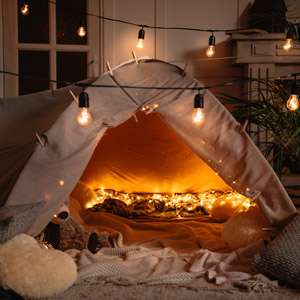 handmade tent with blankets, pillows, toys and lights in room