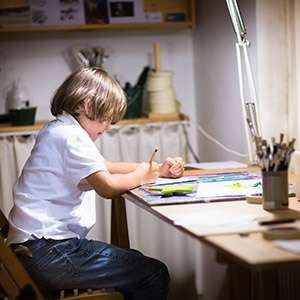 Little boy painting in a dark room late in the evening