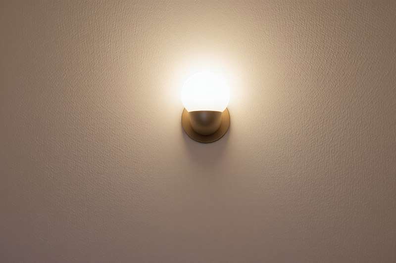 One LED wall light lit up against the wall it is affixed to