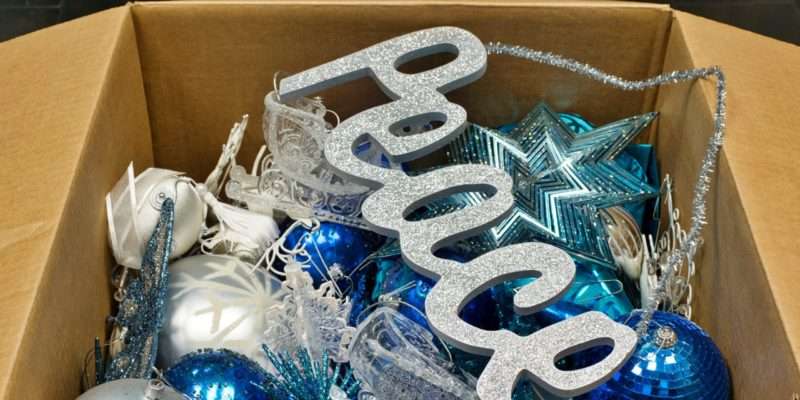 Christmas ornaments and a peace sign decoration in an open cardboard box packed away after the new year, low angle view.