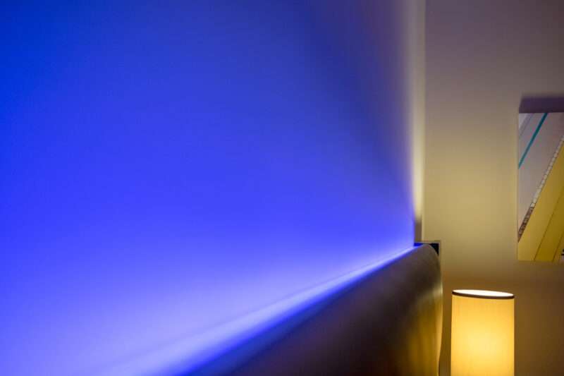 Ambient blue lighting seen illuminated behind a headboard in a luxury apartment.
