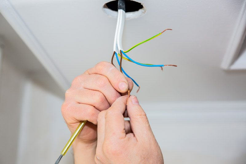 Man is making electrical insulator. Light bulb wires with adhesive tape. Maintenance repair works in the flat. Restoration indoors.